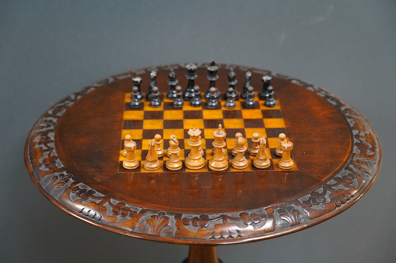 A Victorian carved walnut games table and chess pieces, table 74cm tall, king 6cm tall. Condition - good